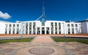 Parliament House of Australia forecourt with Aboriginal design in front and Australian flag.