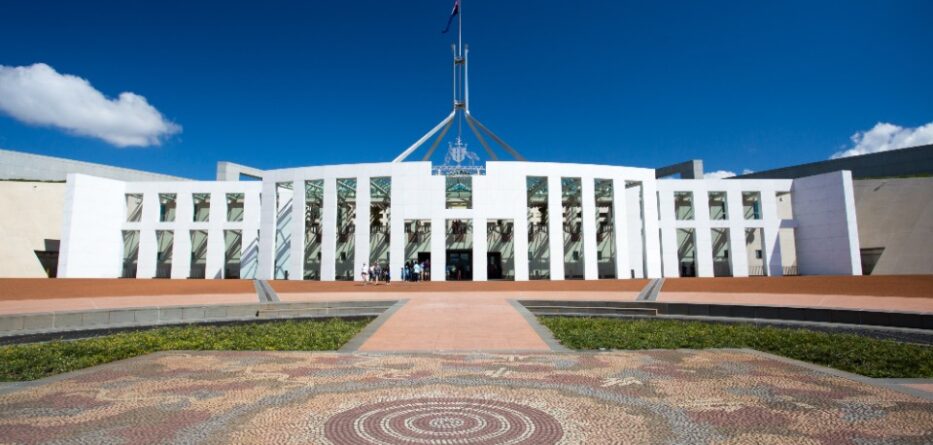 Parliament House of Australia forecourt with Aboriginal design in front and Australian flag.