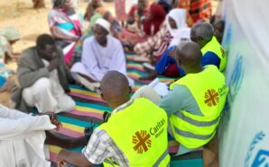 Aid workers sit with Sudanese refugees in Chad. Photo credit: Caritas Mongo.