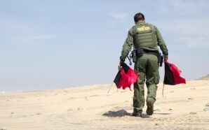 Man carrying border patrol flags. Image: Pixabay.